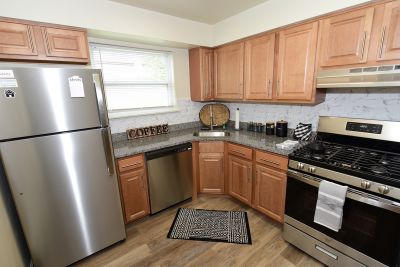 Photo of a refurbished kitchen at Florida Grove Manor showing new cabinets, stainless steel appliances, granite countertops and luxury LVT woodgrain flooring.