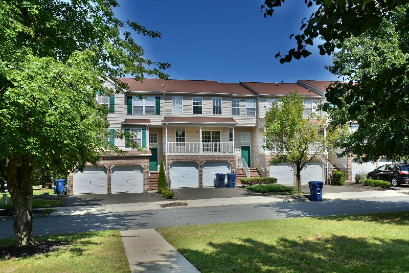 Yorkshire Meadows exterior photo showing several balconies with garages underneath the apartments. Several bushes and trees highlight the landscape.