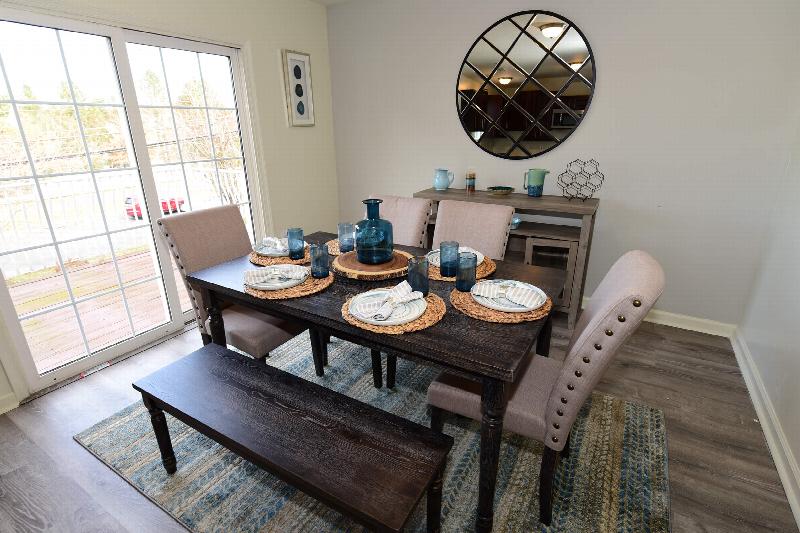 Yorkshire Meadows Dining room photo showing a table for 6, with plate settings and wall decorations. There is a large sliding glass door leading to a balcony.