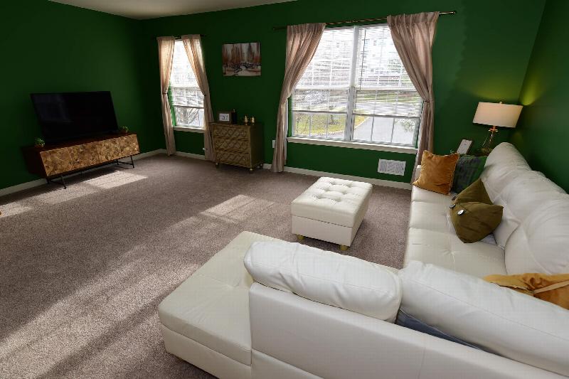 Photo of Yorkshire Meadows Living Room featuring a sectional couch, large TV, wall decorations and 2 windows allowing natural light to fill the room.