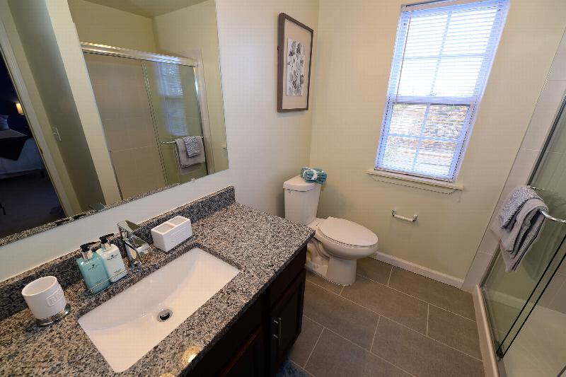 Bathroom at Yorkshire Meadows showing a shower stall with glass sliding doors, new toilet, sink with granite countertops and ceramic tile floor.
