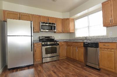 Homestead Village kitchen photo showing wood grain flooring, maple color cabinets, stainless steel appliances and granite countertops.