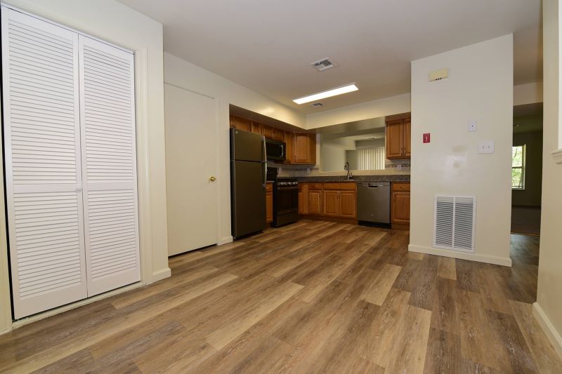 Photo of an eat-in kitchen are at Evergreen forest showing vinyl wood plank flooring, granite countertops, new appliances, new cabinets and mosaic tile backsplash.