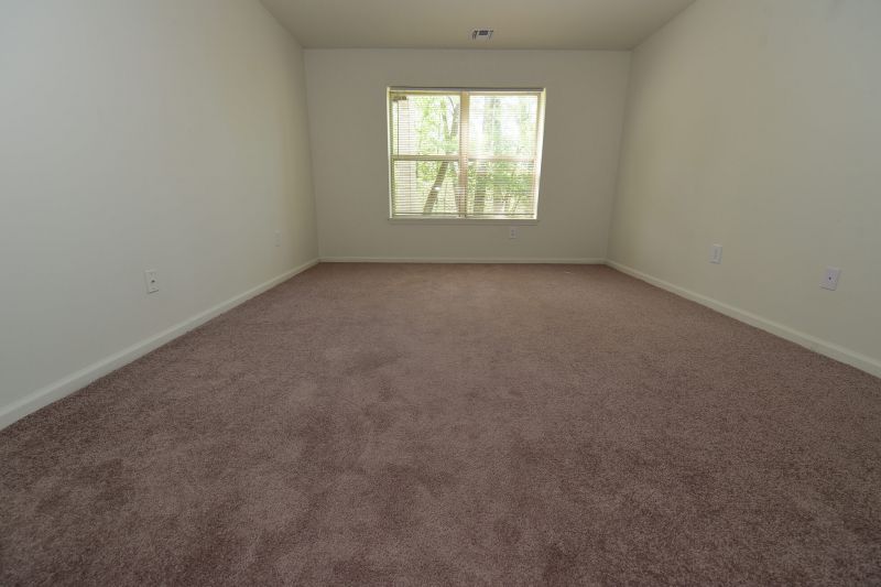 Image of a renovated bedroom at Evergreen Forest with new carpeting, newly painted walls, and a window to allow for fresh air and natural light.