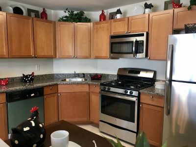 The Glen at Renaissance photo of the kitchen sows cabinets with granite countertops and stainless steel appliances. Many small decorations are on display.
