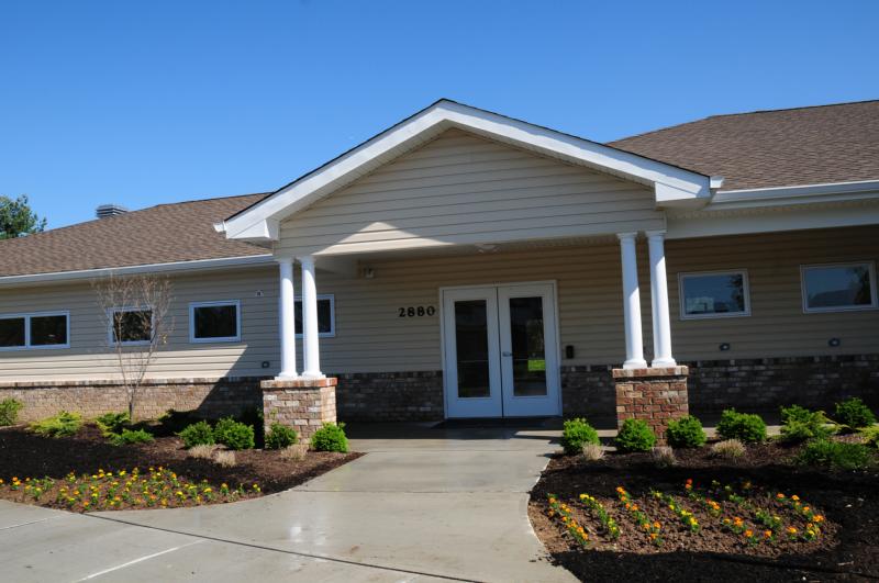 North Brunswick Manor photo showing the Clubhouse. Several bushes highlight the landscape.