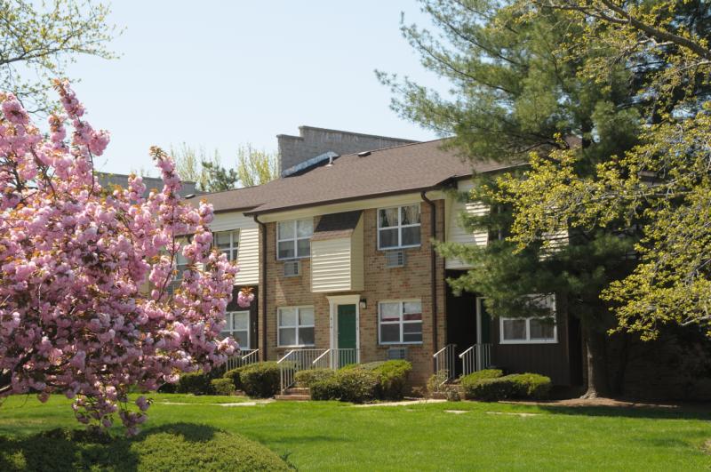 North Brunswick Manor Exterior photo showing a brick exterior and several apartment entrances. Several bushes highlight the landscape.