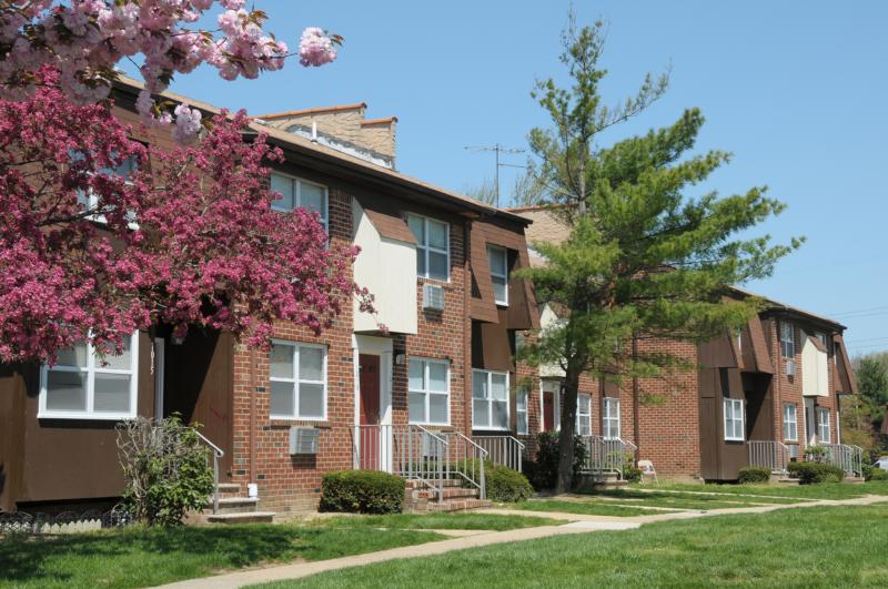 North Brunswick Manor Exterior photo showing a brick exterior and several apartment entrances. Several bushes highlight the landscape.