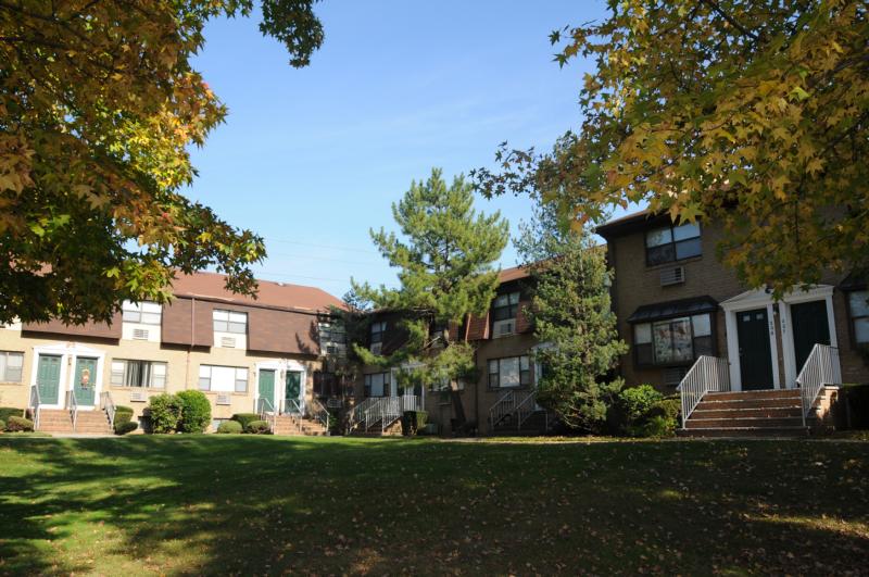North Brunswick Manor Exterior photo showing a brick exterior and several apartment entrances. Several bushes highlight the landscape.