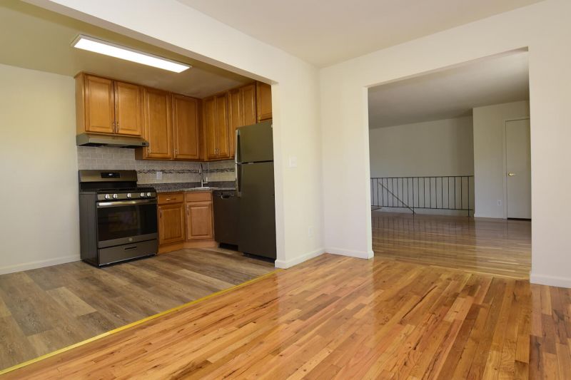 Photo of renovated kitchen showing wood grain tile flooring, new cabinets with granite counter tops and a stainless steel appliance package.