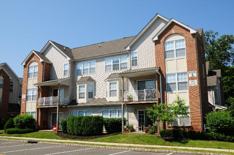 Renaissance Manor Exterior photo showing a brick and vinyl exterior and several balconies. Several bushes and trees highlight the landscape.
