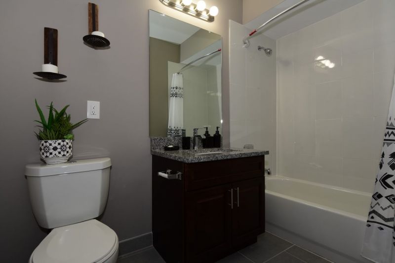 Maebrook at Renaissance interior photo of a bathroom showing new tile flooring, new shower and tub, new toilet, new vanity with granite countertop and a large wall mirror.