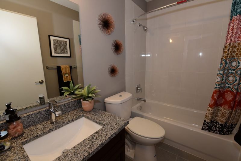 Maebrook at Renaissance interior photo of a bathroom showing new tile flooring, new shower and tub, new toilet, new vanity with granite countertop and a large wall mirrir.