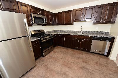 Woodhaven Terrace Kitchen photo showing espresso cabinets, granite counter tops, stainless steel appliances and ceramic tile flooring.