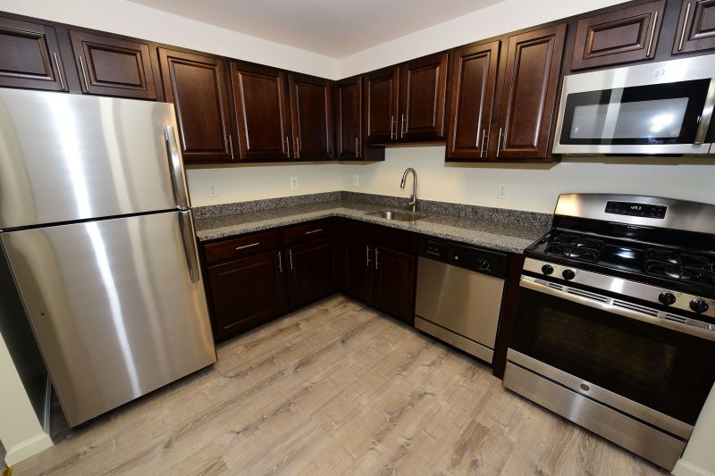 Woodhaven Terrace Kitchen photo showing espresso cabinets, granite counter tops, stainless steel appliances and laminate flooring.