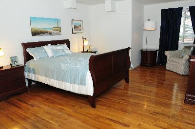 Harbortown Terrace bedroom photo showing a queen sized bed with two night stands, a seating area and a dresser.