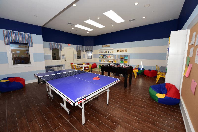 Photo of Harbortown community play room located in the Club House. There is a ping pong table, foosball table, bean bag seating, a children's craft table, various toys and books.