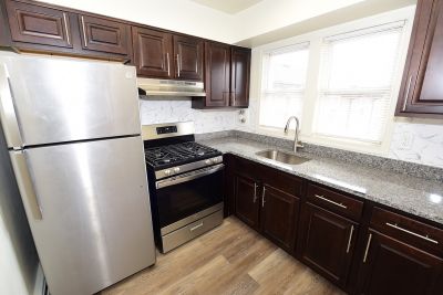 Photo of a refurbished kitchen at Convery Gardens showing new cherry cabinets, stainless steel appliances, granite countertops and luxury LVT woodgrain flooring.