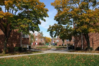 State Fayette Exterior photo showing a brick exterior. There is a pathway that leads to apartment entrances. Several bushes and trees highlight the landscape.
