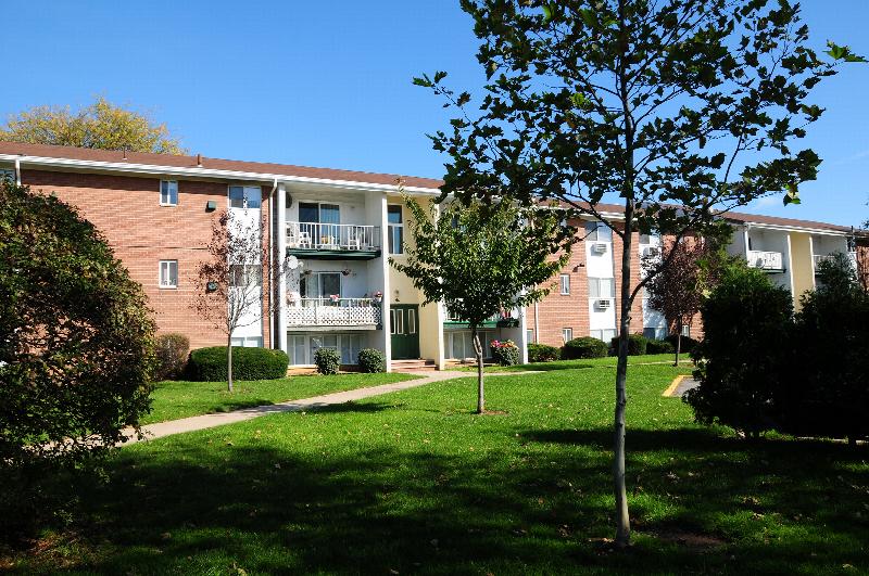 State Fayette Exterior photo showing a brick exterior and several balconies. Several bushes and trees highlight the landscape.