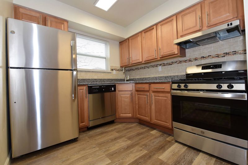 Photo of renovated kitchen showing wood grain tile flooring, new cabinets with granite counter tops and a stainless steel appliance package.