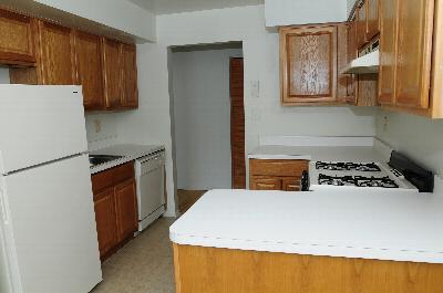 Hidden Village image of a kitchen showung maple cabinets, white countertops and appliances.