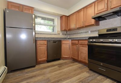Photo of renovated kitchen showing wood grain tile flooring, new cabinets with granite counter tops and a stainless steel appliance package.