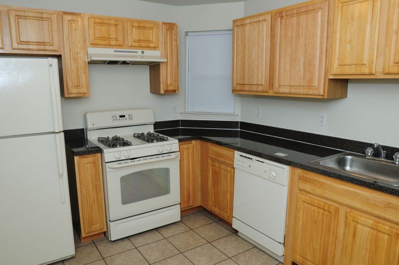 Harbortown Ports kitchen photo showing light cabinets with a dark granite countertop and white appliances.