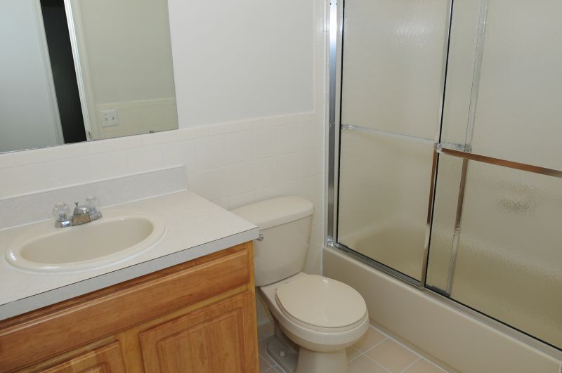 Harobortown Ports photo of a bathroom showing a tub with sliding shower doors, a toilet, vanity with sink and a mirror above.