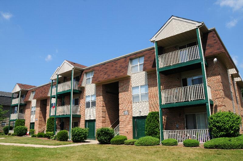 Rivendell Village Exterior photo showing a brick and vinyl exterior and several balconies. Several bushes and trees highlight the landscape.