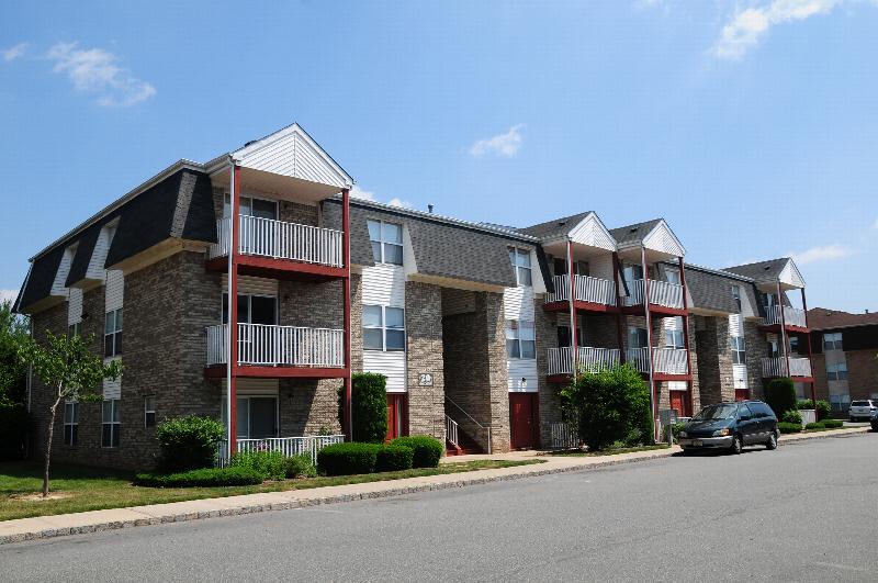 Rivendell Village Exterior photo showing a brick and vinyl exterior and several balconies. Several bushes and trees highlight the landscape.