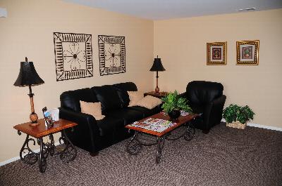 Rivendell Village Living Room photo showing a couch, a chair and two end tables surrounding a center table. There are lamps on the end tables and decorations throughout the room.