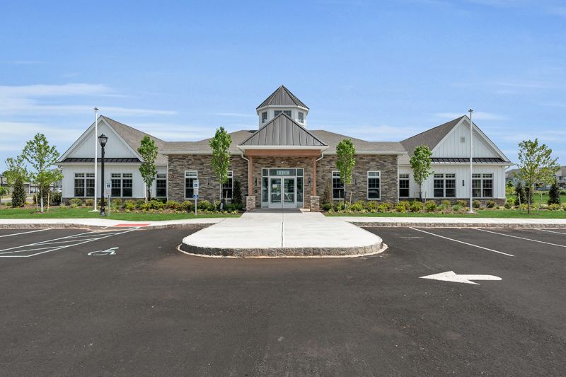 Exterior image of the Rivendell Club House, showing a large building with stone front, white siding, black roof and covered entry.