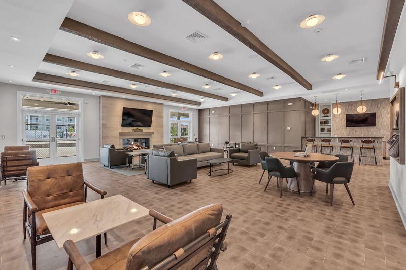 Interior image of the community room at the Rivendell Club House showing multiple seating areas for congregating with friends, a large fire place, and counter seating at the kitchen area.