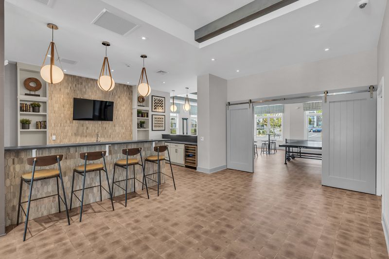 Interior image of the community room at the Rivendell Club House showing counter seating at the kitchen area and a large doorway leading to the game room.