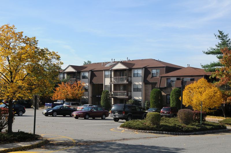 Woodbridge Center Plaza photo shows one of the large parking area for residents. One of the apartment buildings is shown behind the parking lot.