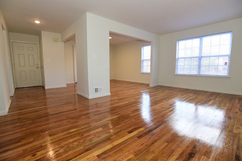 Woodbridge Center Plaza interior photo shows gleaming hardwood floors throughout the living space. Several large windows allow in natural light.