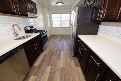 Photo of renovated kitchen showing wood grain tile flooring, new cabinets with granite counter tops and a stainless steel appliance package.