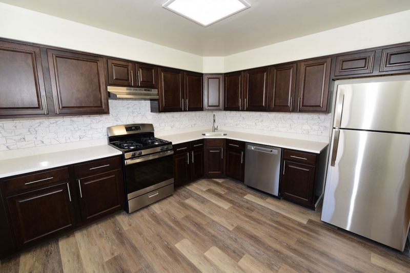 Photo of renovated kitchen showing wood grain tile flooring, new cabinets with granite counter tops and a stainless steel appliance package.