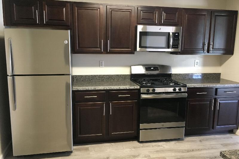 Fox Hill Run interior photo of the renovated kitchen, showing cherry cabinets, granite countertops, stainless steel appliances and wood grain flooring.