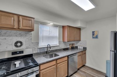 Cloverleaf Gardens photo shows the kitchen in a refurbished apartment with luxury vinyl tile flooring, new cabinets, granite countertops ad stainless steel appliances.