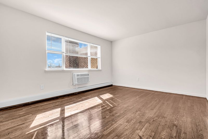 Interior photo of the bedroom at Cloverleaf Gardens showing another angle of the luxury hardwood floors and a large window that fills the space with natural light.