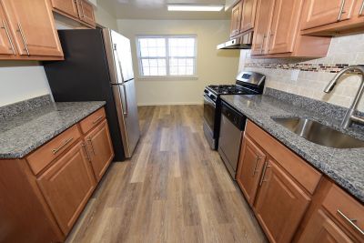 Photo of renovated kitchen showing wood grain tile flooring, new cabinets with granite counter tops and a stainless steel appliance package.