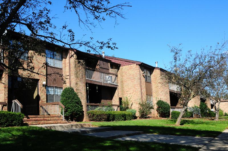 Woodbridge Terrace Exterior photo showing a brick exterior and several balconies. Several bushes and trees highlight the landscape.