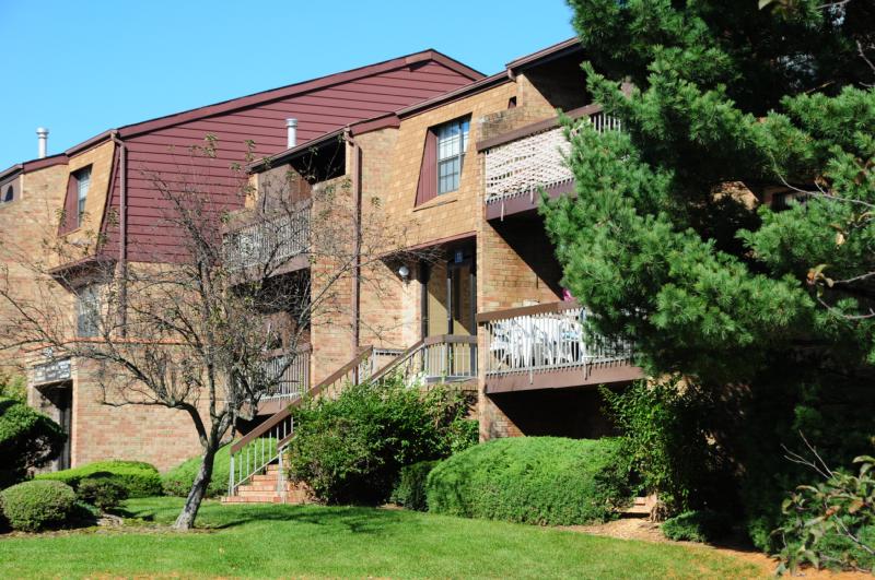 Woodbridge Terrace Exterior photo showing a brick exterior and several balconies. Several bushes and trees highlight the landscape.