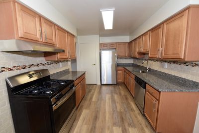 Photo of renovated kitchen showing wood grain tile flooring, new cabinets with granite counter tops and a stainless steel appliance package.