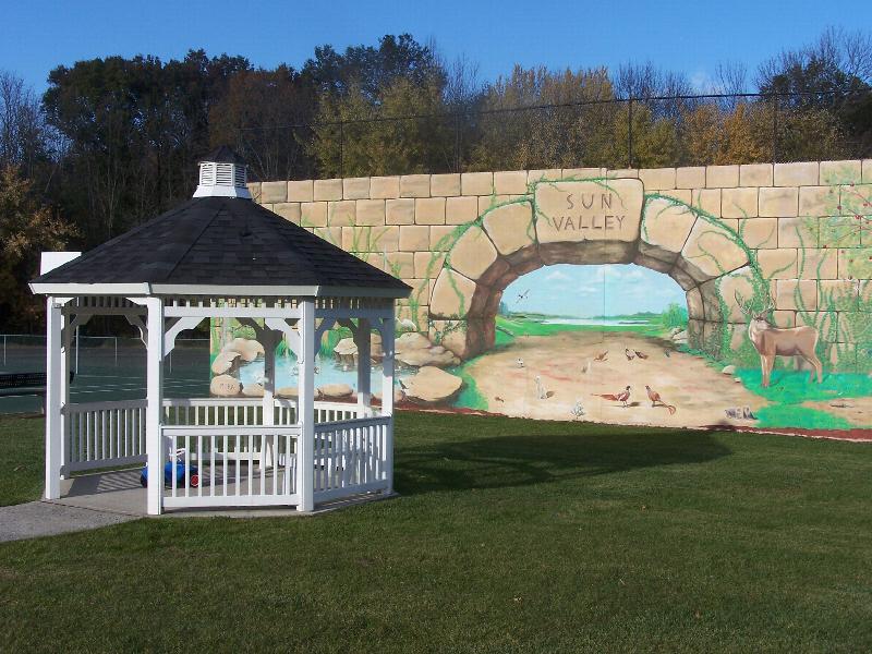 Photo of a gazebo located on the Sun Valley property with a large mural painted wall behind it.
