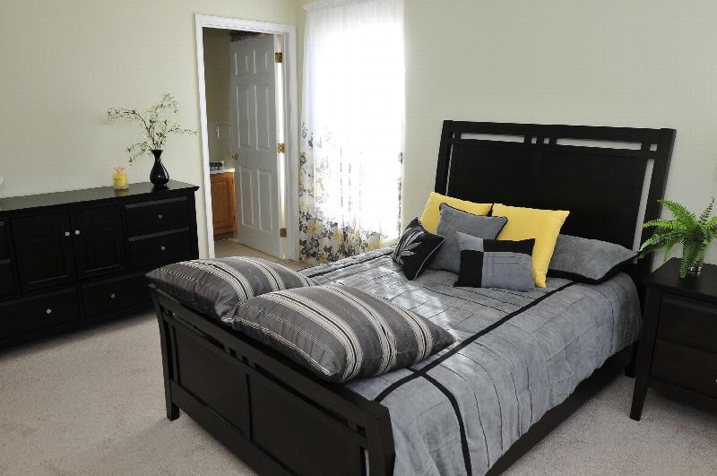 Sun Valley Affordable bedroom photo showing a bed with a nightstand and a dresser. There is a door leading to an adjoining bathroom. A window allows for natural light.