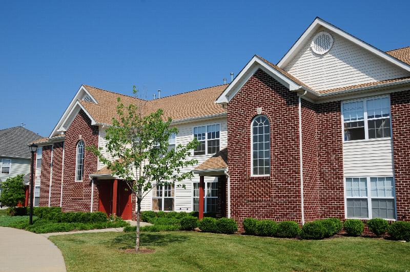 Rivendell Heights Affordable Exterior photo showing a brick and vinyl exterior and a street light. There is a pathway that leads to apartment entrances. Several bushes and trees highlight the landscape.