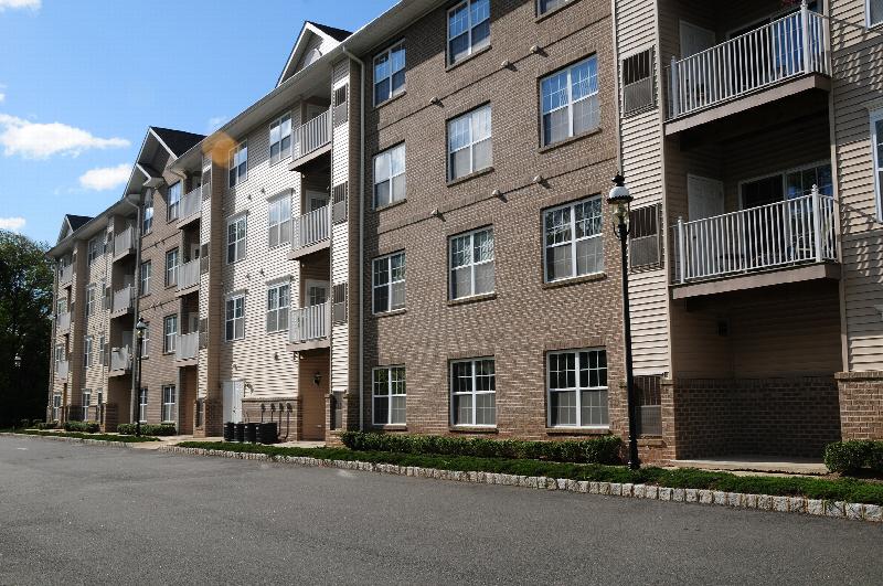 Side view photo of the exterior of Park Terrace apartment building, showing a 4 level building with brick and siding, and many private balconies.